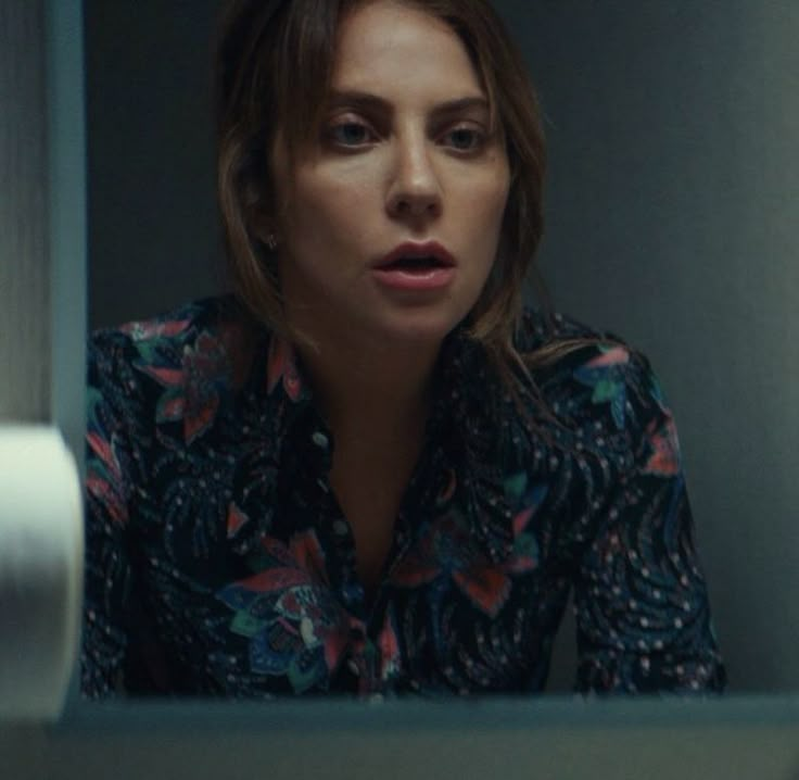 a woman in a floral shirt looking at the camera with an intense look on her face