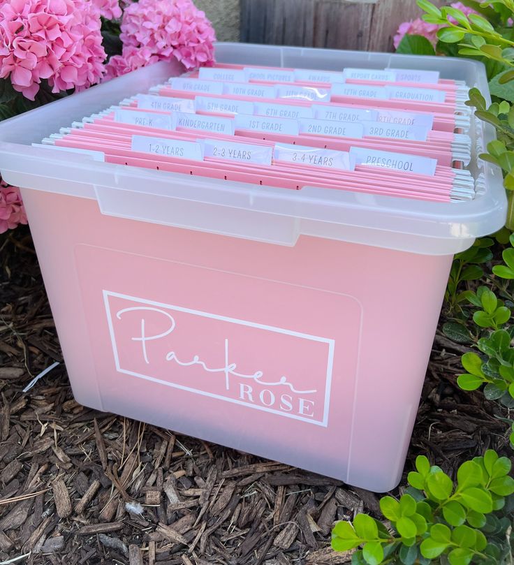 a pink plastic box filled with files next to flowers