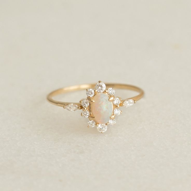 an opal and diamond ring on a white surface