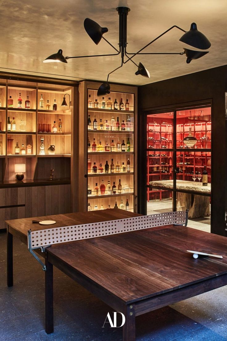 a ping pong table in the middle of a room with shelves full of liquor bottles