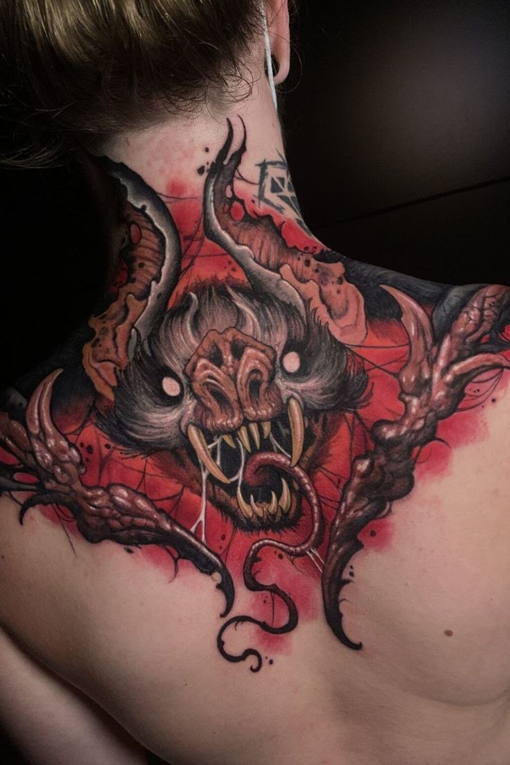 the back of a woman's neck with tattoos on it and an evil demon