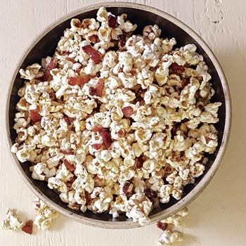 a bowl filled with popcorn sitting on top of a white table next to a wall