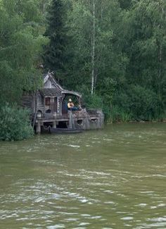 two people are sitting on the back of a houseboat in the middle of a river