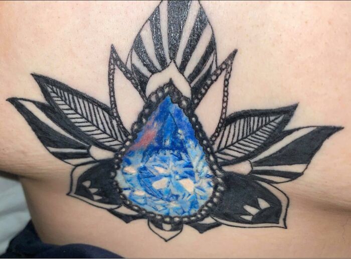 a man with a tattoo on his stomach has a blue diamond in the center of it