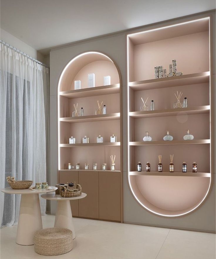 an empty room with shelves and vases on the wall next to a table in front of a window