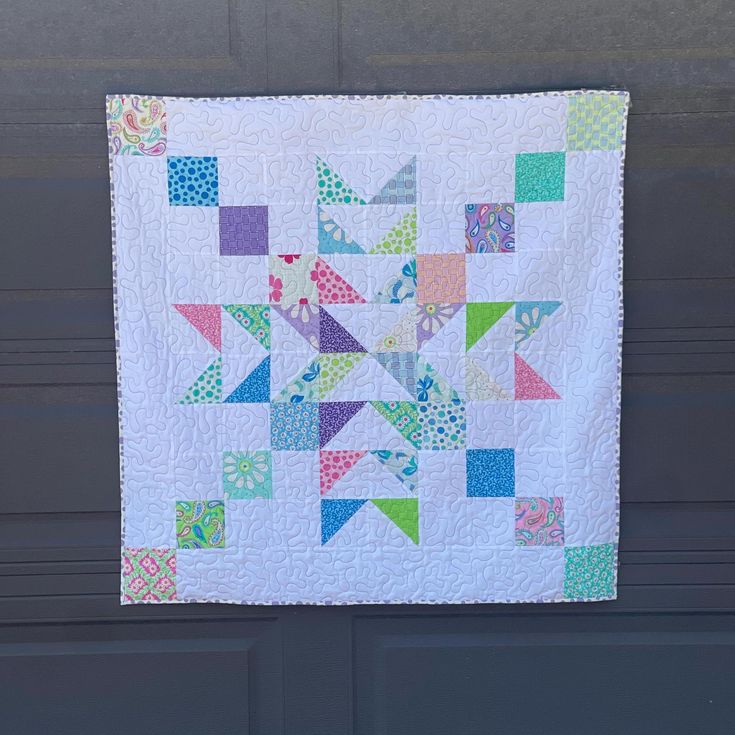 a quilted wall hanging on the side of a garage door with an arrow design