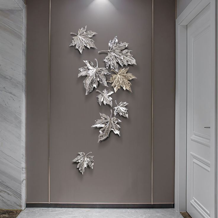 the wall is decorated with metal leaves and has a white marble floor in front of it