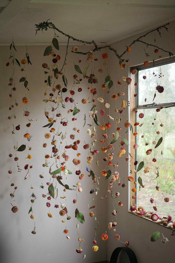 a room with flowers hanging from the ceiling and a window in front of it,