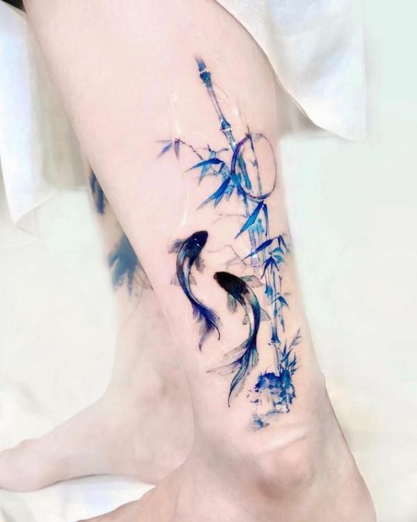 a woman's leg with blue watercolors on it and an artistic tattoo design