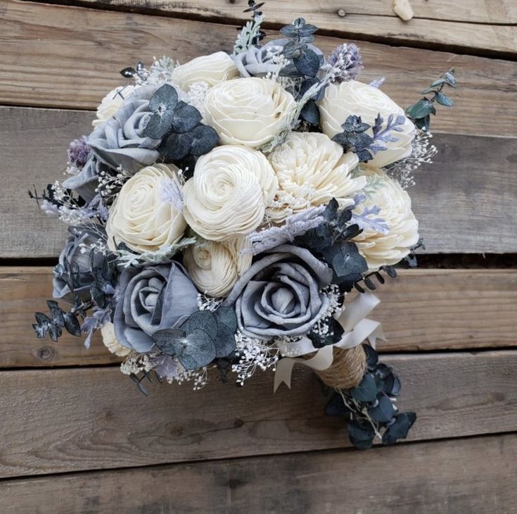 a bridal bouquet with white and blue flowers on a wooden background, ready to be used as a wedding bouquet