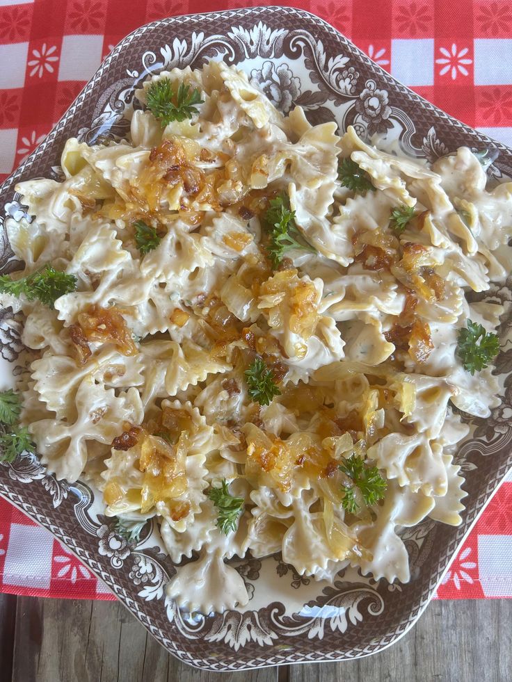 a plate filled with pasta and broccoli on top of a checkered table cloth