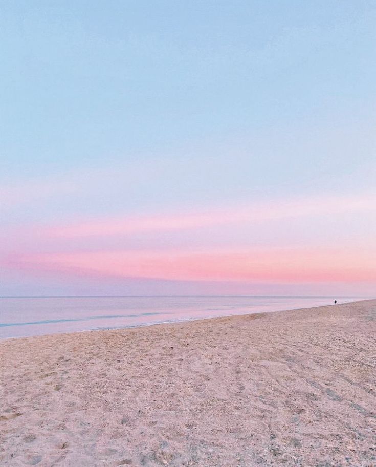 an empty beach at sunset with the ocean in the background