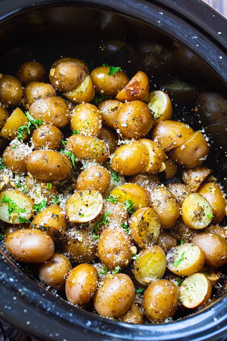 cooked potatoes with parmesan sprinkles in a crock pot on a wooden table