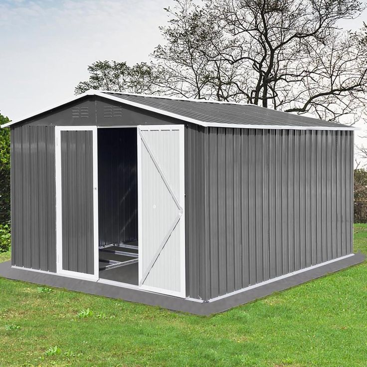 a gray shed sitting on top of a lush green field