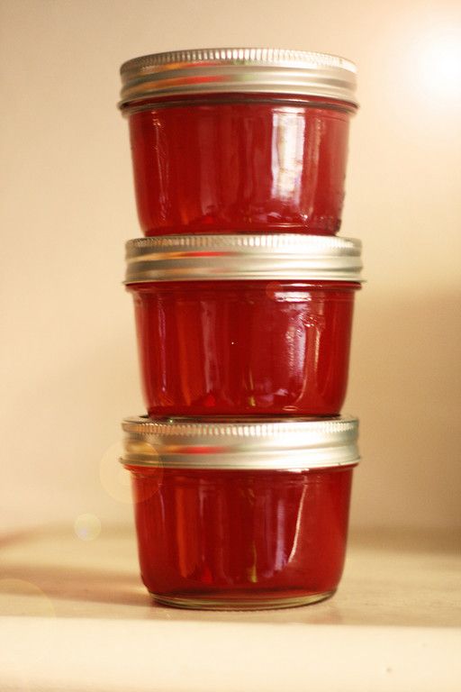 three jars filled with red liquid sitting on top of a white counter next to each other