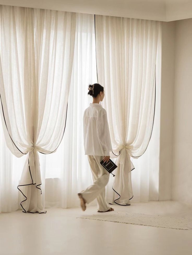 a woman is walking in front of some curtains