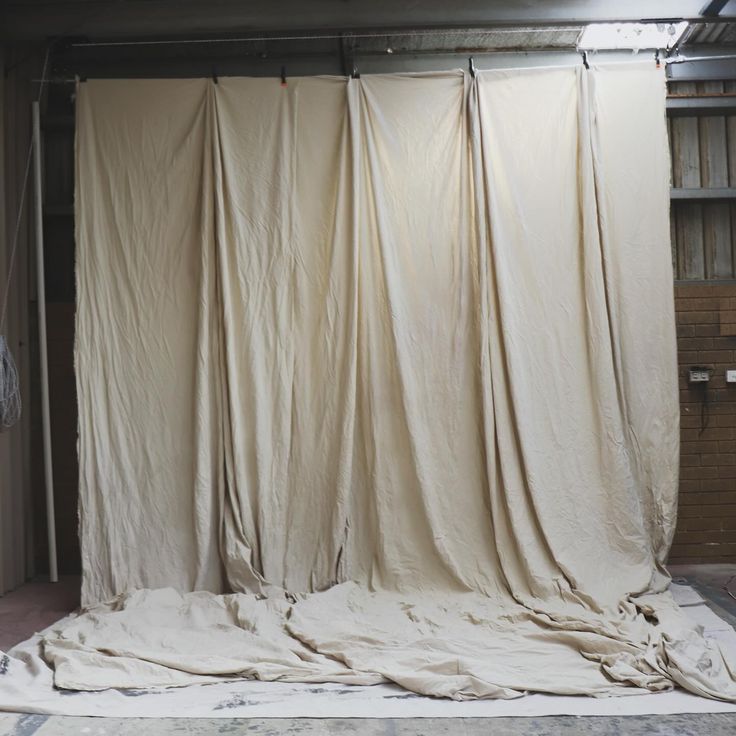 a room that has some curtains on the floor in front of it and is covered with white fabric