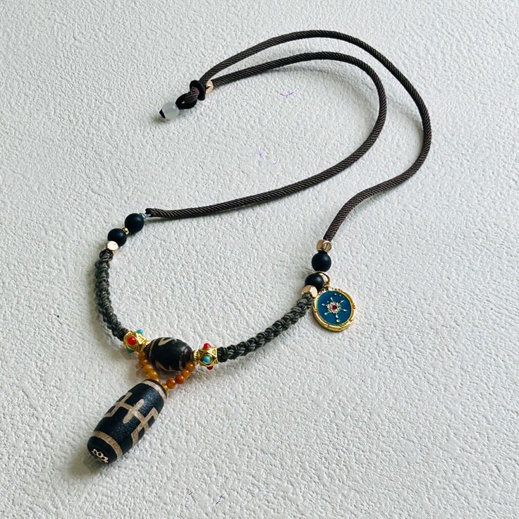 Aristocrat Dzi-bead Necklace Traditional Brown Beaded Pendant Necklace, Brown Amulet Pendant Jewelry, Brown Amulet Style Round Pendant Necklace, Brown Amulet Style Necklace With Round Pendant, Brown Amulet Necklace With Round Pendant, Handmade Brown Amulet Beads, Black Amulet Style Beaded Necklaces, Traditional Brown Jewelry With Black Beads, Traditional Adjustable Black Bead Necklaces