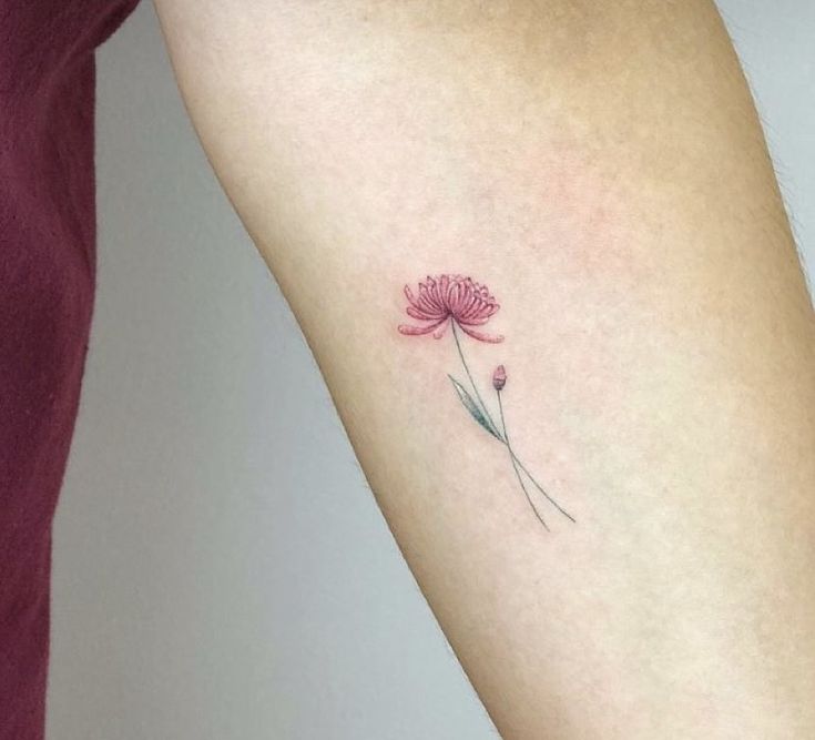 a woman's arm with a pink flower tattoo on it