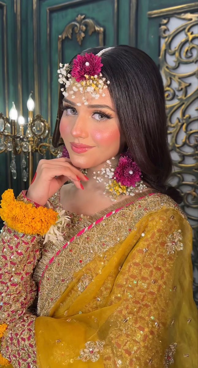 a woman wearing a yellow and pink outfit with flowers in her hair is posing for the camera