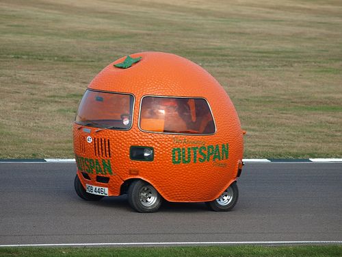 an orange bus driving down the road with people in it's back seat and windows