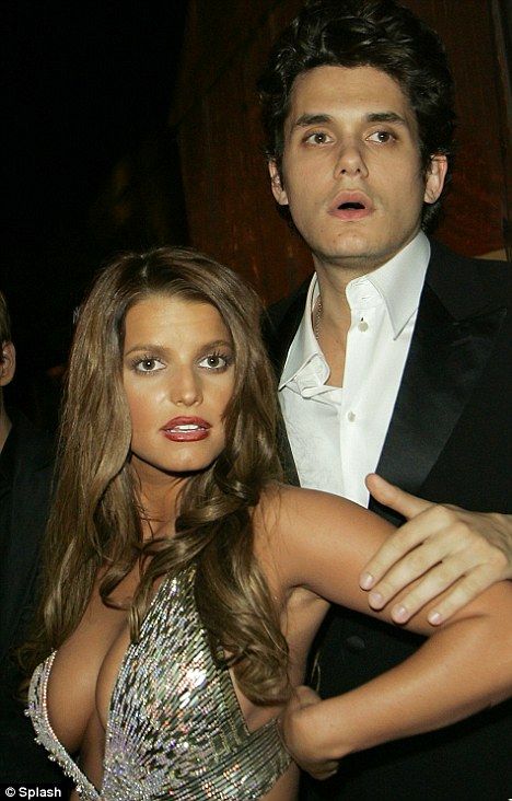 a man standing next to a woman in a silver dress and tuxedo at a party