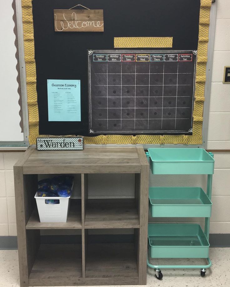 a classroom desk with shelves and bins in front of the chalkboard that says welcome