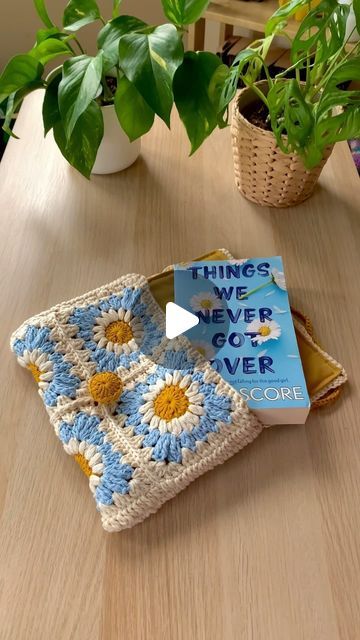 there is a crochet book on the table next to a potted plant