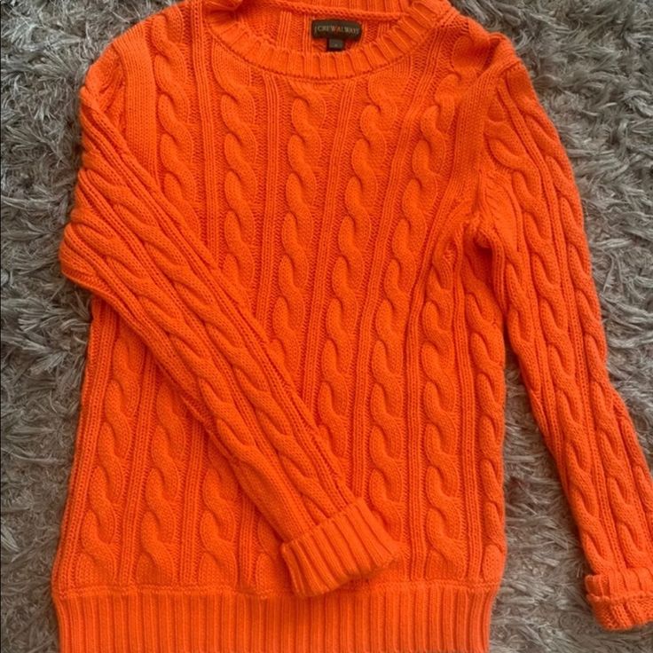 an orange sweater is laying on the floor