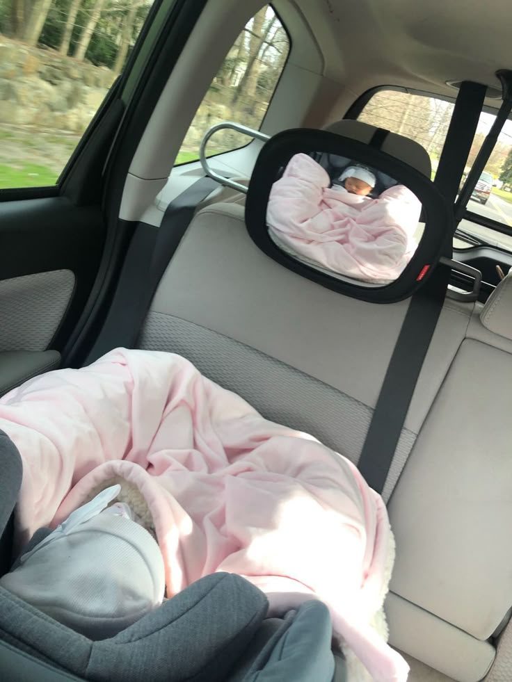 an infant in a car seat with a pink blanket on it's back end