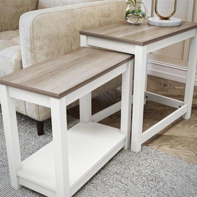 two wooden tables sitting next to each other on top of a carpeted floor in front of a couch