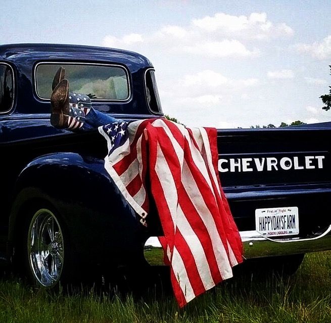 an american flag draped on the back of a blue truck