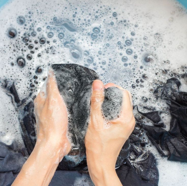 someone is washing their hands in a blue tub with soapy water and black cloths