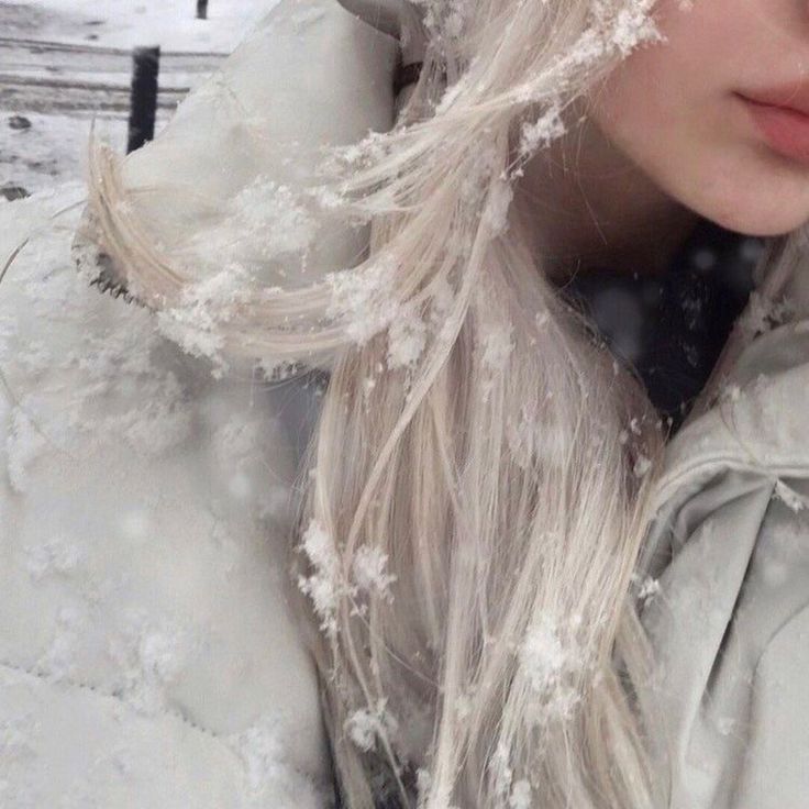 a woman with long blonde hair standing in the snow