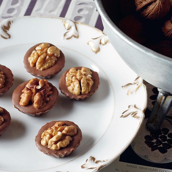 there are chocolates with walnuts on the top and nuts in the middle sitting on a white plate