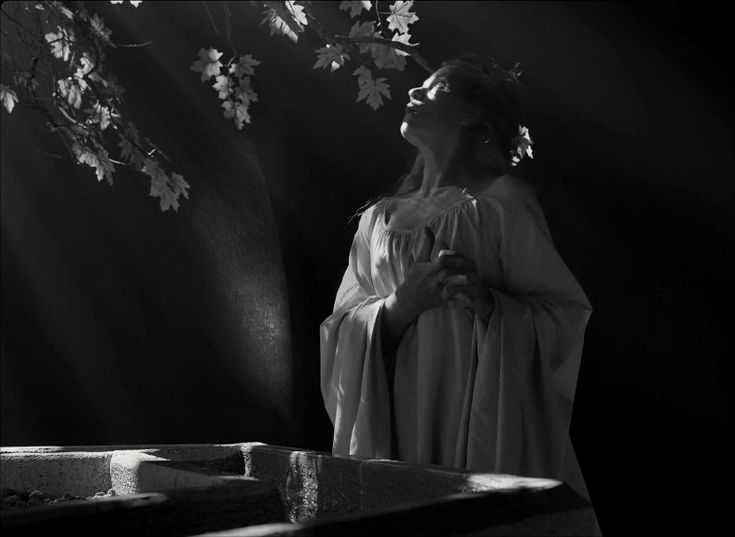 a woman in white dress standing next to a tree