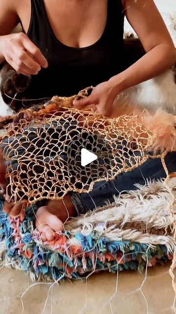 a woman sitting on the floor working on some fabric with scissors and yarn in front of her