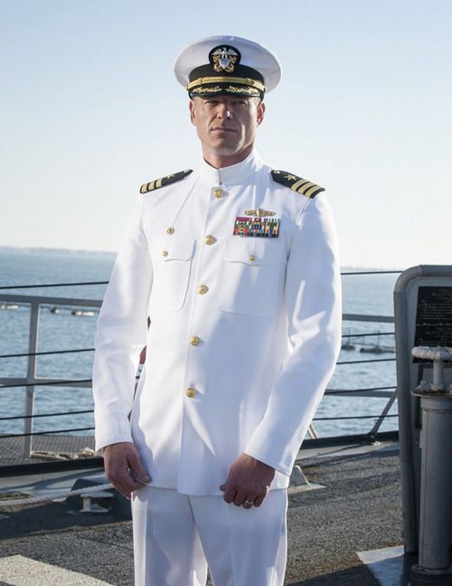 a man in uniform standing on the deck of a ship