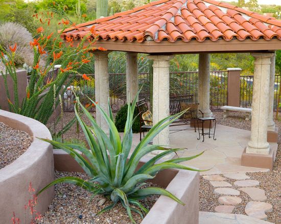 an outdoor gazebo surrounded by plants and rocks