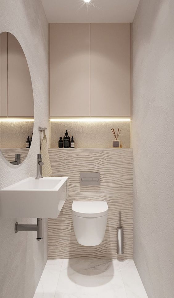 a white toilet sitting next to a sink in a bathroom under a round light fixture