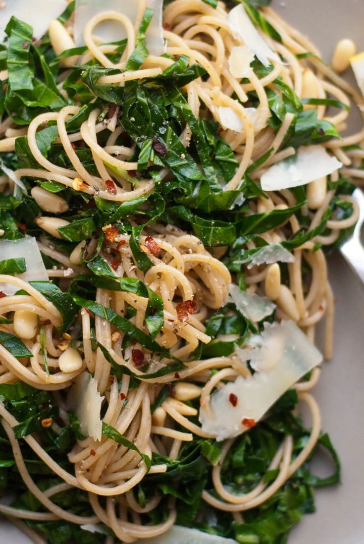 a white plate topped with pasta and greens