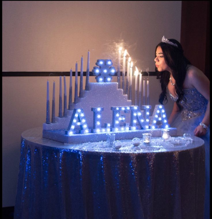 a woman standing in front of a cake with lit letters on it that spell out alder