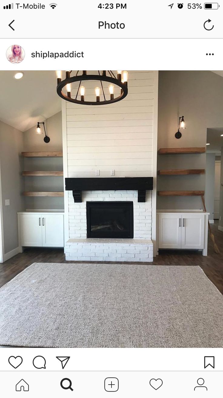 an empty living room with a fireplace and shelves