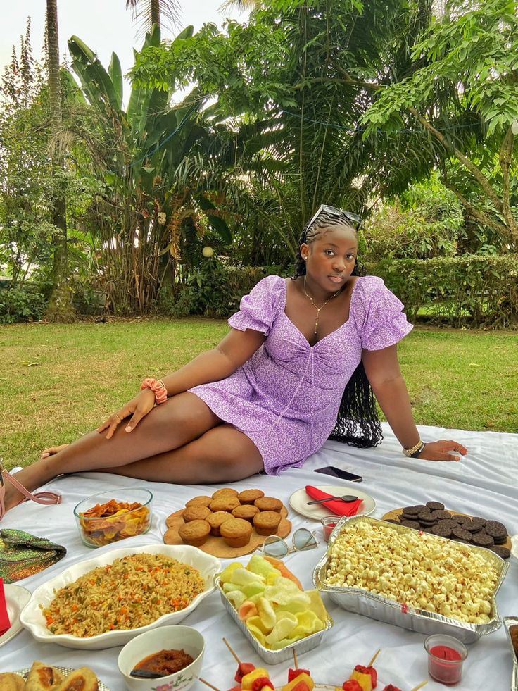 a woman sitting on the ground in front of a table filled with different types of food