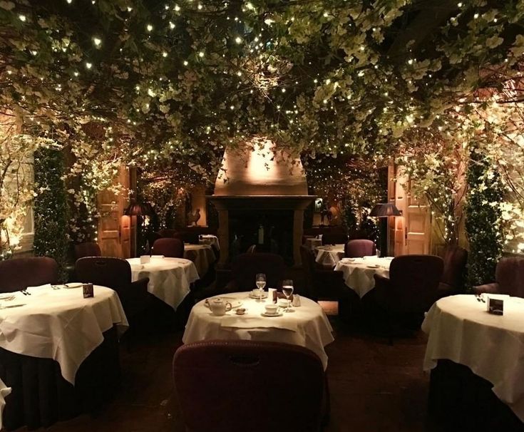 the dining room is decorated with greenery and lite - up tables for dinner