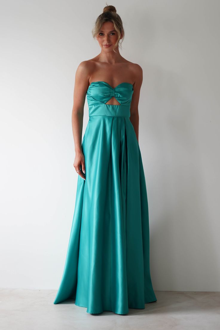 a woman in a strapless teal gown poses for the camera with her hands on her hips