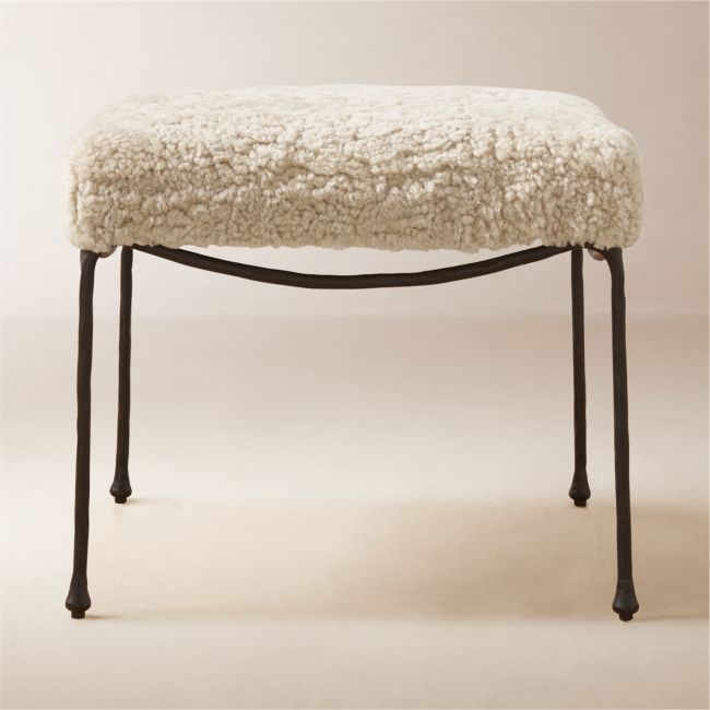 a sheep stool sitting on top of a white floor next to a black metal frame