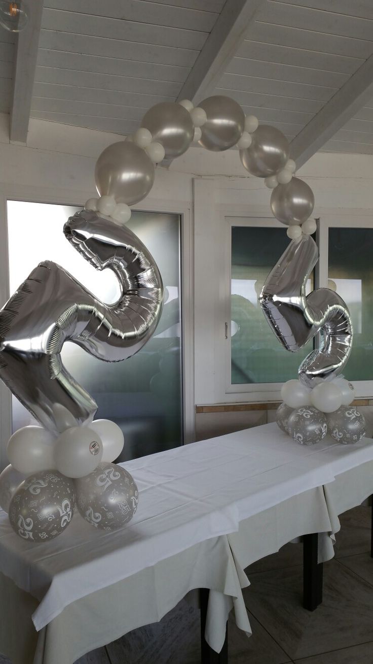 the table is set with balloons and silver decorations