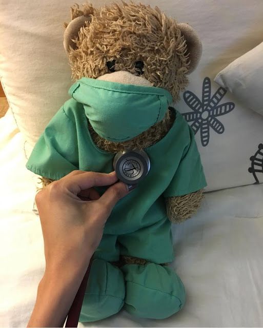 a person is holding a stethoscope in front of a teddy bear on a bed