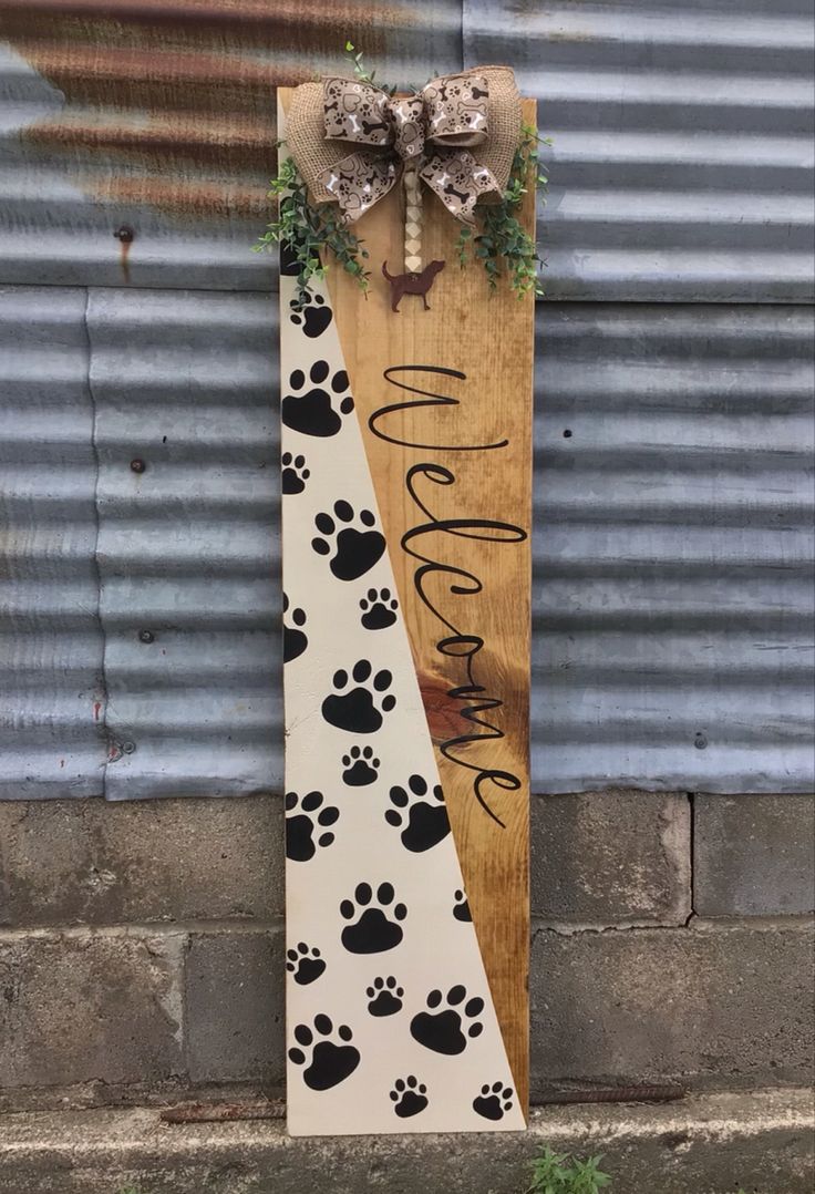 a wooden sign that says welcome with paw prints on it and a bow at the top